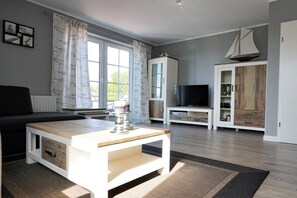 A living room with a sofa, a coffee table, a television, and cabinets. - Baltic Sea residence Barendorf (Barendorf\/Dassow)
