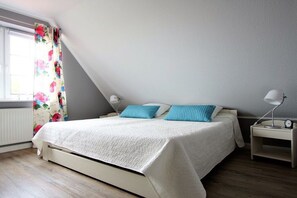 A bedroom with a bed, a nightstand, a lamp, and a window with curtains. - Baltic Sea residence Barendorf (Barendorf\/Dassow)