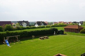 A residential area with houses, a grassy yard, a swing set, and picnic tables. - Baltic Sea residence Barendorf (Barendorf\/Dassow)