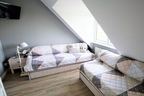 A bedroom with a sloped ceiling, a bed with a quilted headboard, a bedside lamp, and a window. - Baltic Sea residence Barendorf (Barendorf\/Dassow)