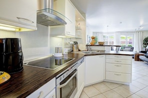 A modern kitchen with a built-in oven, a coffee machine, and a large window providing natural light. - Strandkieker Achtern (St. Peter-Ording)