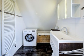 A compact laundry room with a washing machine, a sink, and a mirror. - Strandkieker Achtern (St. Peter-Ording)