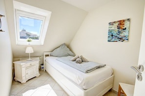 A bedroom with a bed, a nightstand, a window, and a painting on the wall. - Strandkieker Achtern (St. Peter-Ording)