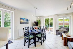 A dining area with a table and chairs, a television, and a view of the outdoors. - Strandkieker Achtern (St. Peter-Ording)