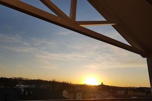 A sunset view from a balcony with a clear sky, houses in the background, and a metal structure in the foreground. - Apartment building Miramare (Ostseebad Kühlungsborn)