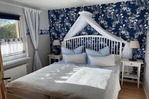 A bedroom with a canopy bed, white bedding, and floral wallpaper. - Holiday apartment with 3 bedrooms (Boltenhagen\/Redewisch)