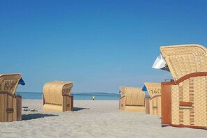 A row of wicker beach chairs with numbers on them, arranged on a sandy beach. - Holiday home with 3 bedrooms (Hohwacht (Ostsee))