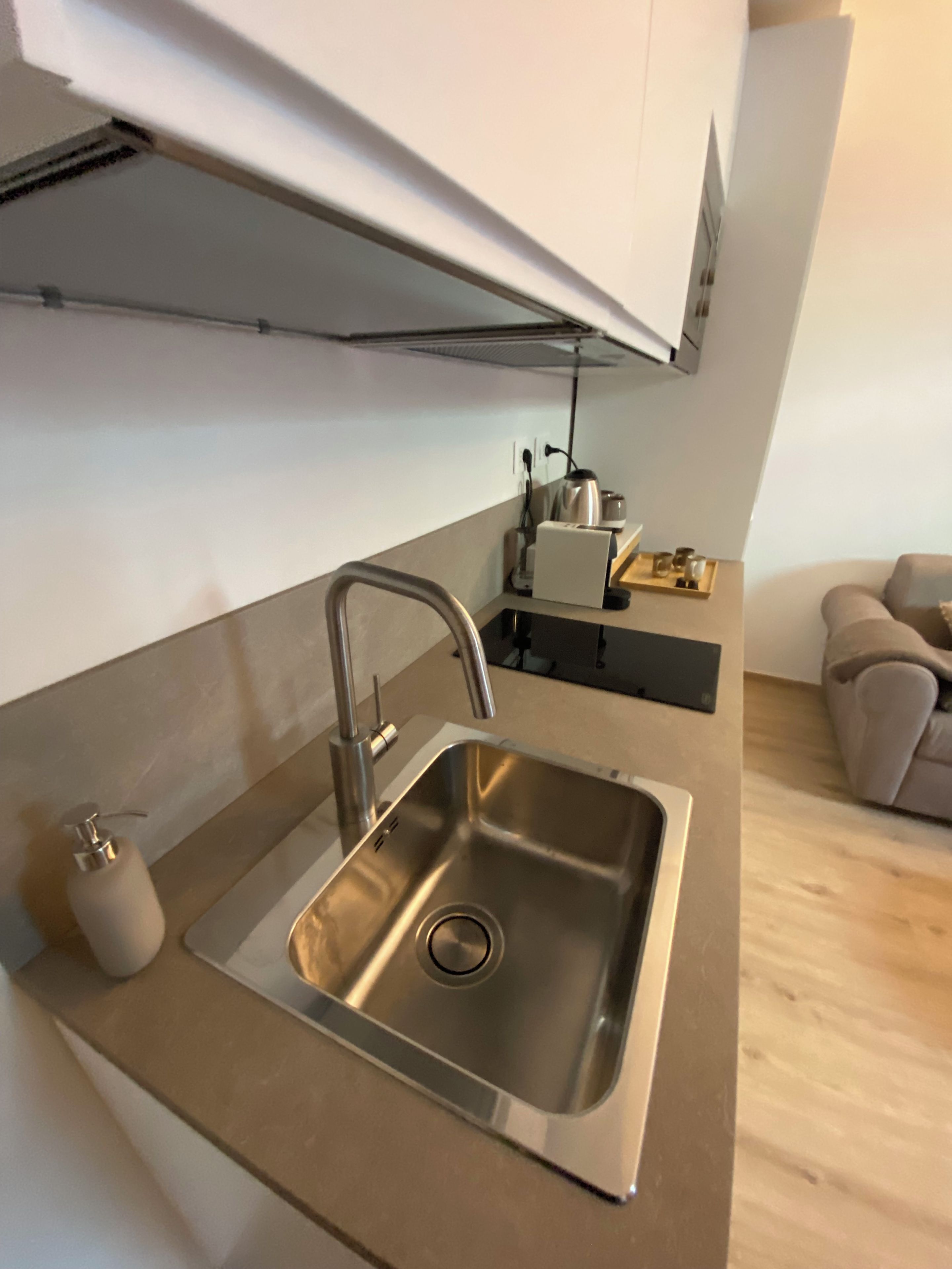 A modern kitchen with a stainless steel sink, a built-in oven, and a compact countertop.