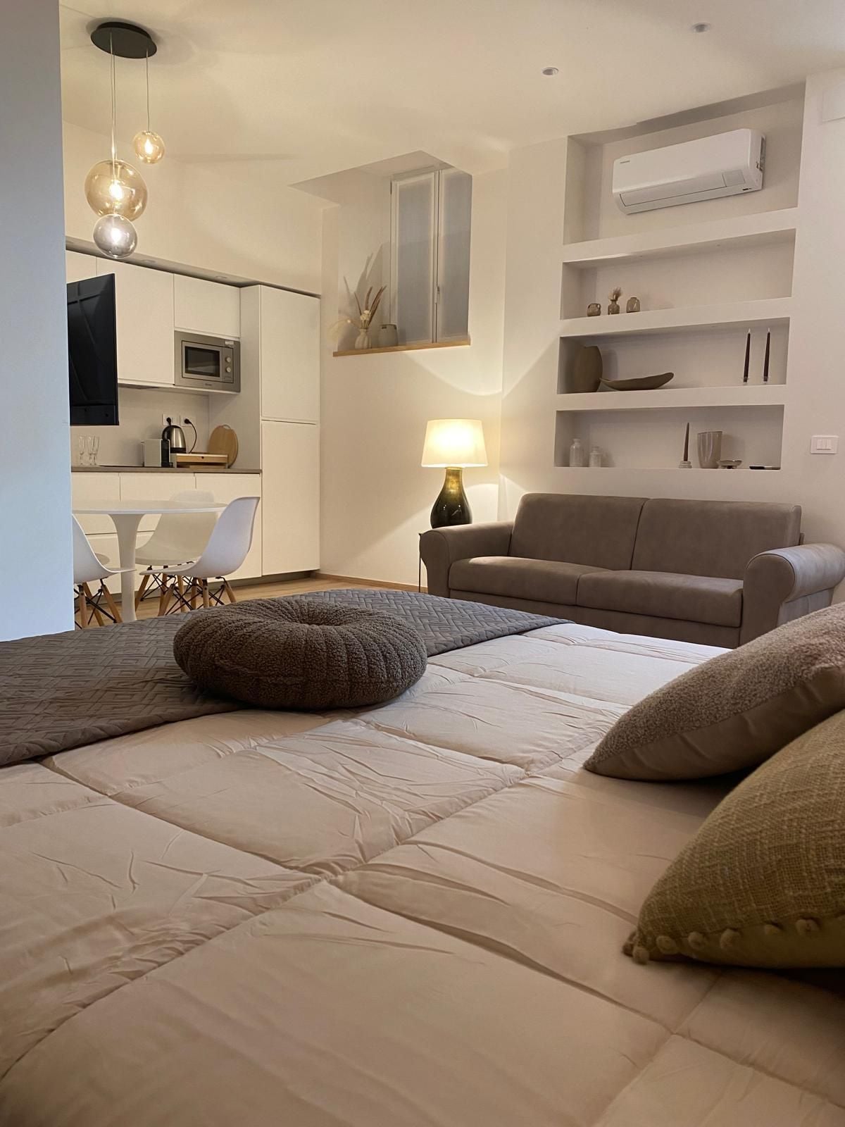 A modern bedroom with a bed, a sofa, a desk, and a lamp.