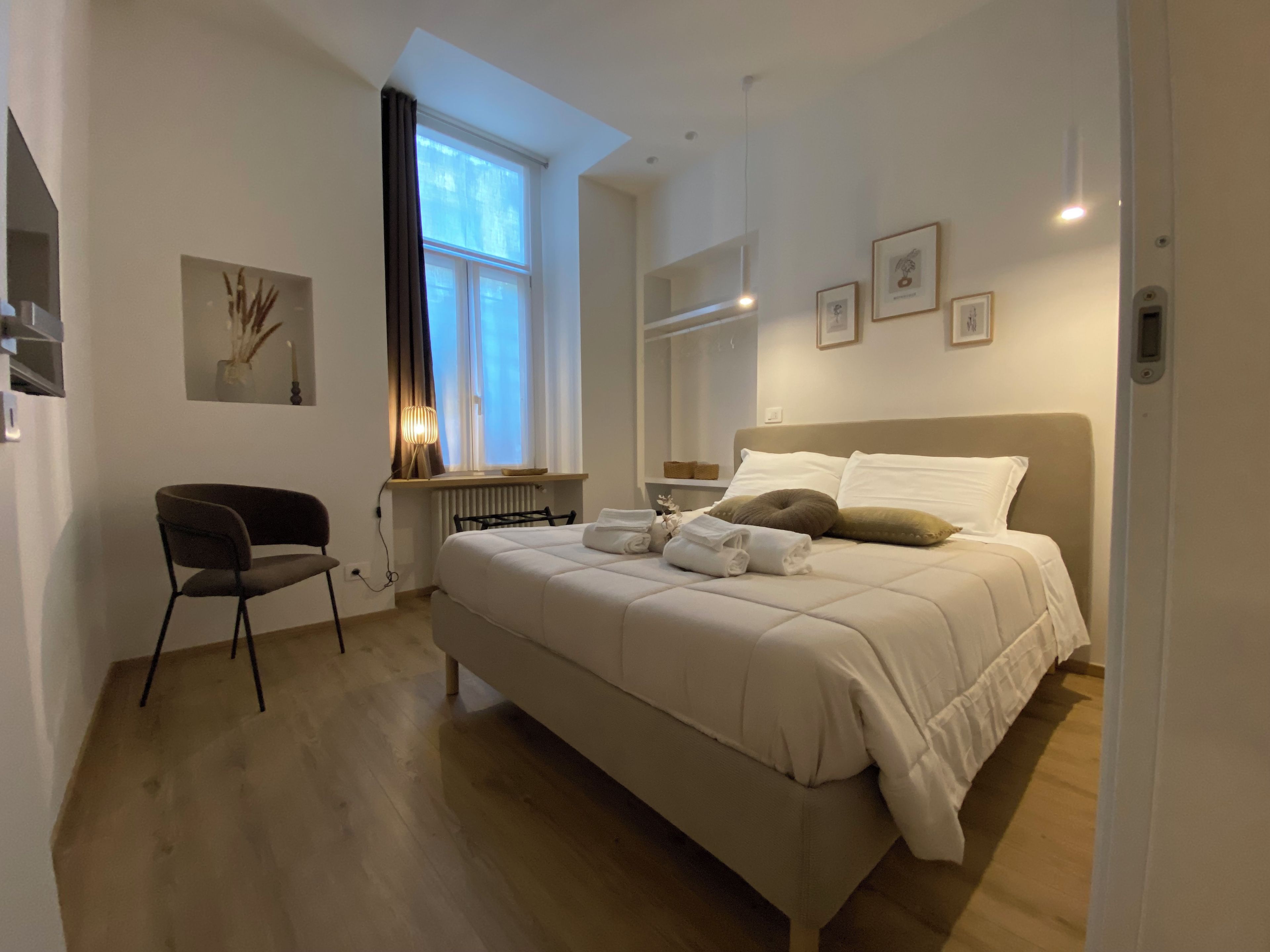 Une chambre moderne avec un grand lit, une chaise, une fenêtre avec des rideaux et un radiateur.