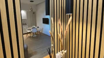 A modern interior with a wooden slatted wall, a round mirror, and a small table with decorative items.