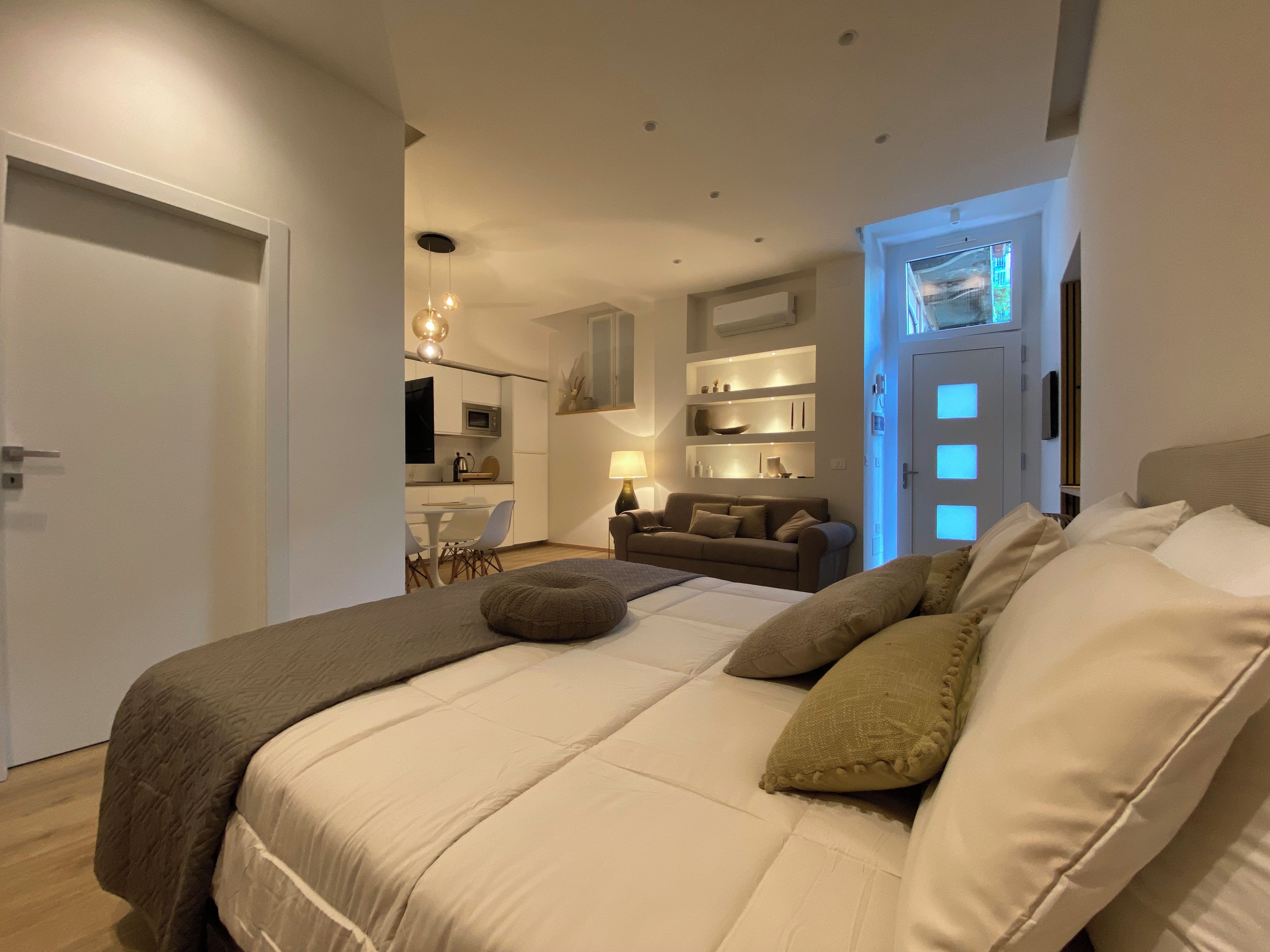 Un dormitorio moderno con una cama grande, un sofá y un área de comedor al fondo.
