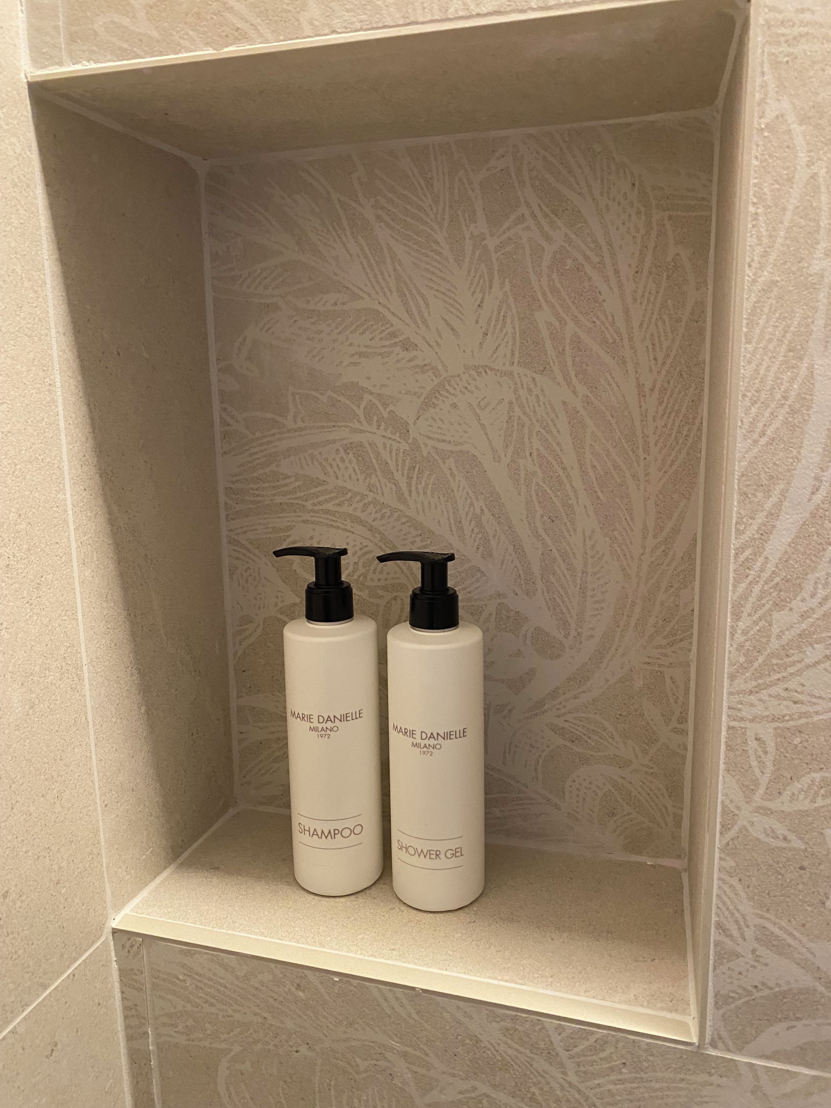 Un estante de baño con dos productos de Marie Danielle: uno etiquetado como champú y el otro como gel de ducha.