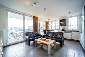 Een moderne woonkamer met een zithoek, een salontafel en een keukenhoek met een magnetron.