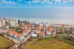 Un quartier résidentiel comprenant plusieurs immeubles d’appartements, une plage et un ciel dégagé.