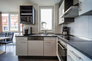 Een moderne keuken met een inbouwoven, een koffiezetapparaat en een raam dat natuurlijk licht binnenlaat.