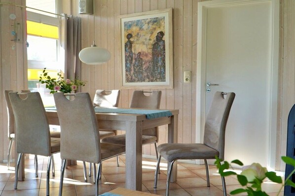 Ein Essbereich mit einem Holztisch und Stühlen, einer Hängelampe und einem Bild an der Wand.