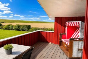 En röd balkong med utsikt över en grön äng och en klar himmel.