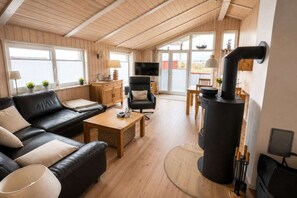 Ein gemütliches Wohnzimmer mit Kamin, Ledersofa, Couchtisch aus Holz und einem Fernseher.