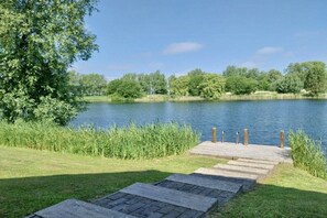A wooden dock leading to a calm lake surrounded by greenery. - Holiday home with 1 bedroom (Otterndorf)