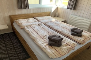 A double bed with a plaid bedspread and two folded towels. - Holiday home with 1 bedroom (Otterndorf)