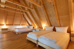 A bedroom with a sloped ceiling, wooden beams, a large bed, bedside tables, and a window. - Holiday home with 3 bedrooms (Mittelangeln OT Havetoftloit)