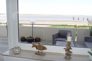 Ein Balkon mit Meerblick, Blumentöpfen, einer Fischskulptur und einem Kerzenständer.