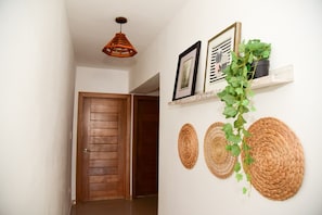 Ein Flur mit einer Holztür, einer hängenden Pendelleuchte und gewebten Körben an der Wand.