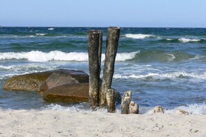 A sandy beach with wooden posts and large rocks. - Holiday apartment with 1 bedroom (Hohwacht)