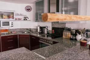 Eine moderne Küche mit Granit-Arbeitsplatten, Edelstahlgeräten und einer Uhr an der Wand.