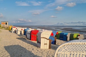A beach with rows of colorful beach chairs and a lifeguard tower. - Holiday home with 2 bedrooms (Wyk auf Föhr)