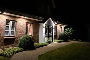 Ein Ziegelhaus mit einer gut beleuchteten Eingangspartei und einem gepflasterten Weg zum Eingang.