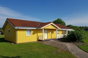 A yellow single-story house with a red-tiled roof, a front porch, and a small front yard. - Holiday home with 2 bedrooms (Otterndorf)