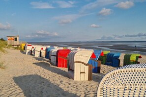 A beach with rows of colorful beach huts and a lifeguard tower. - Holiday home with 2 bedrooms (Wyk auf Föhr)