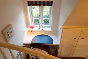 Une petite cuisine avec une fenêtre, un meuble blanc et une lampe rouge.
