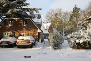 A residential street with snow-covered cars and houses, a clear sky, and leafless trees. - Holiday home with 2 bedrooms (Wyk auf Föhr)