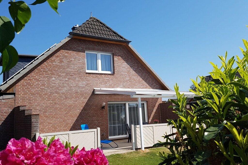 Une maison à deux étages avec une façade en briques, un toit à deux versants et un patio couvert.