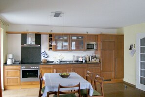 Eine Küche mit Holzausstattung, einer Mikrowelle, einem Backofen und einem Esstisch mit Stühlen.