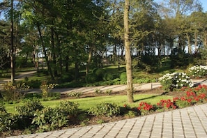 Un jardin aménagé avec un chemin pavé, des haies taillées et des plantes en fleurs.