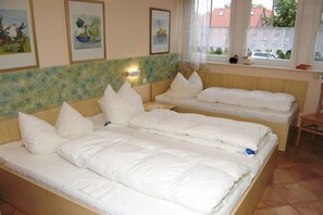 Ein Hotelzimmer mit zwei Einzelbetten, einem Fenster mit Blick nach draußen und Kunstwerken an der Wand.