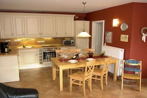 Ein Essbereich mit Holztisch, Stühlen und einer Küche im Hintergrund.