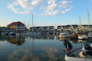 A marina with multiple boats docked, a building with a red roof, and a clear sky. - in the Stolkos holiday home (Trassenheide)