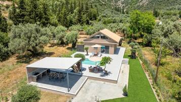 A modern house with a swimming pool, outdoor seating, and a well-maintained lawn.