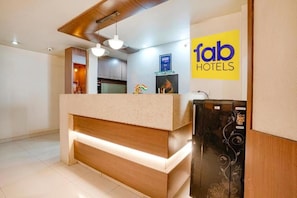 A reception area with a counter, a digital display, and a logo for Fab Hotels.
