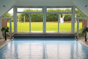 A swimming pool with a view of a grassy yard and a wooden swing set. - Barendorf Beach Suite (Barendorf)
