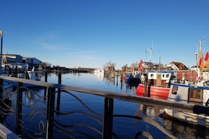 En lugn vattenväg med förtöjda båtar, ett metallräcke i förgrunden och byggnader i bakgrunden.