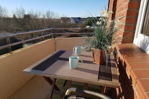 A balcony with a table, two cups, and a potted plant. - Barendorf Beach Suite (Barendorf)