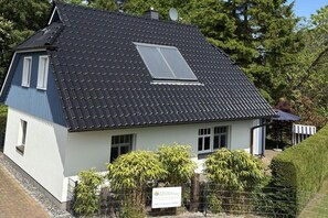 A two-story house with a dark roof, a skylight, and a fenced garden area. - Holiday home with 2 bedrooms (Ostseeheilbad Zingst)