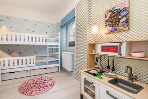 Een kinderkamer met stapelbedden, een kitchenette en een decoratieve wand.
