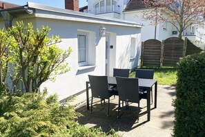 A white building with a patio area featuring a table and chairs. - Holiday apartment Vogelhaus (Binz)